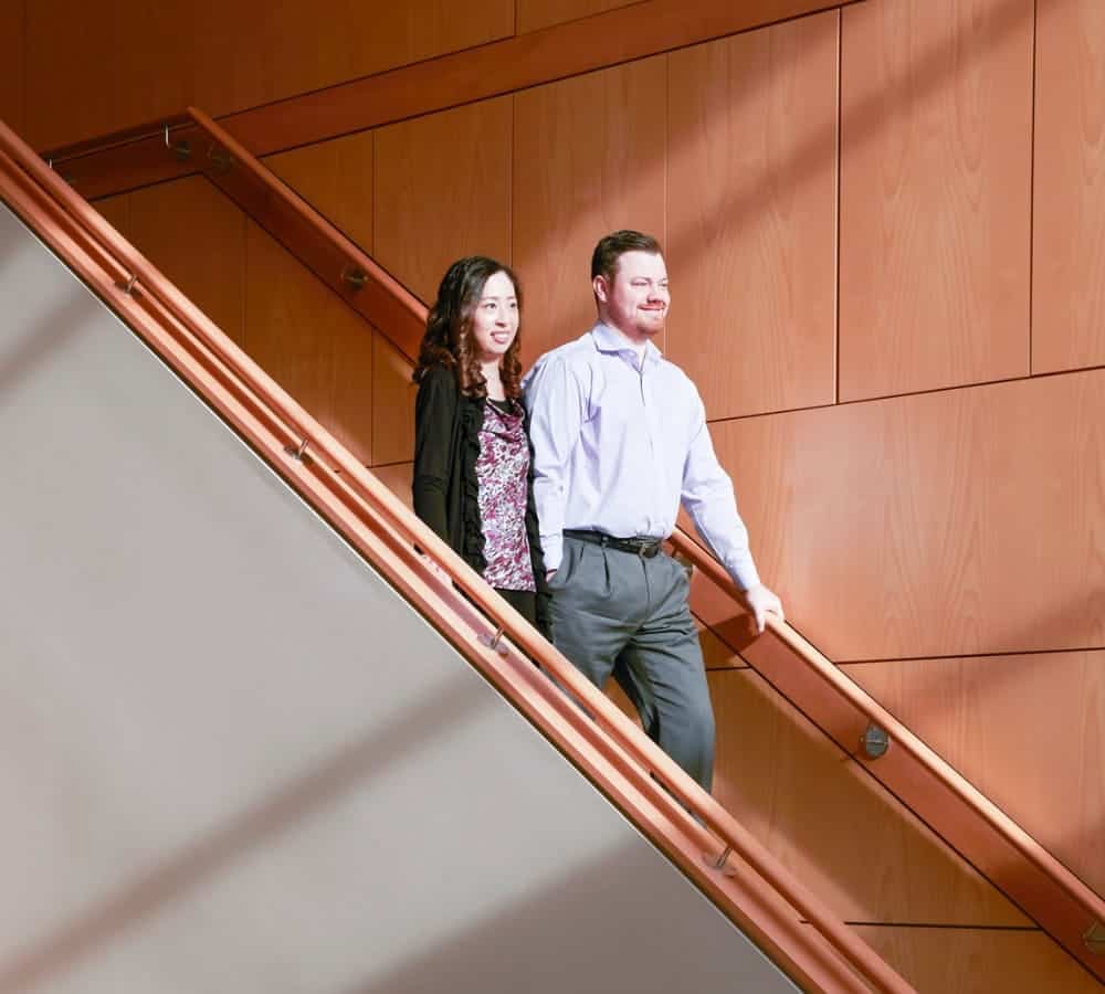 A man and woman walk down a wooden staircase with a wooden facade