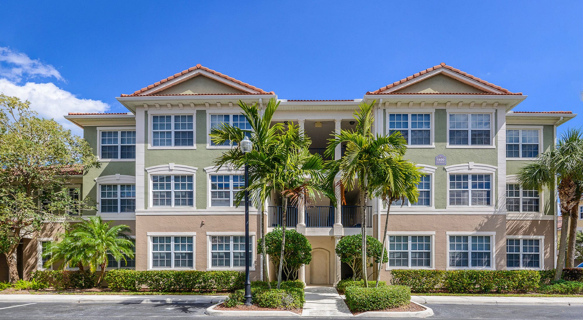Green and tan coastal-style apartments with palm trees